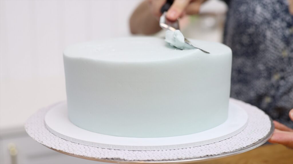 how to get a level top edge of the cake by swiping sideways, going around the cake two or three times
