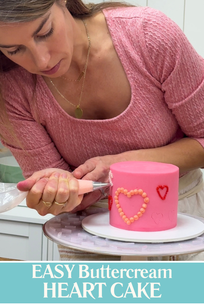 Piping a heart outline onto a cake using buttercream, a simple Valentine’s Day cake idea with piped details