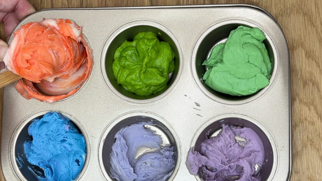 tinting buttercream colors in a cupcake pan