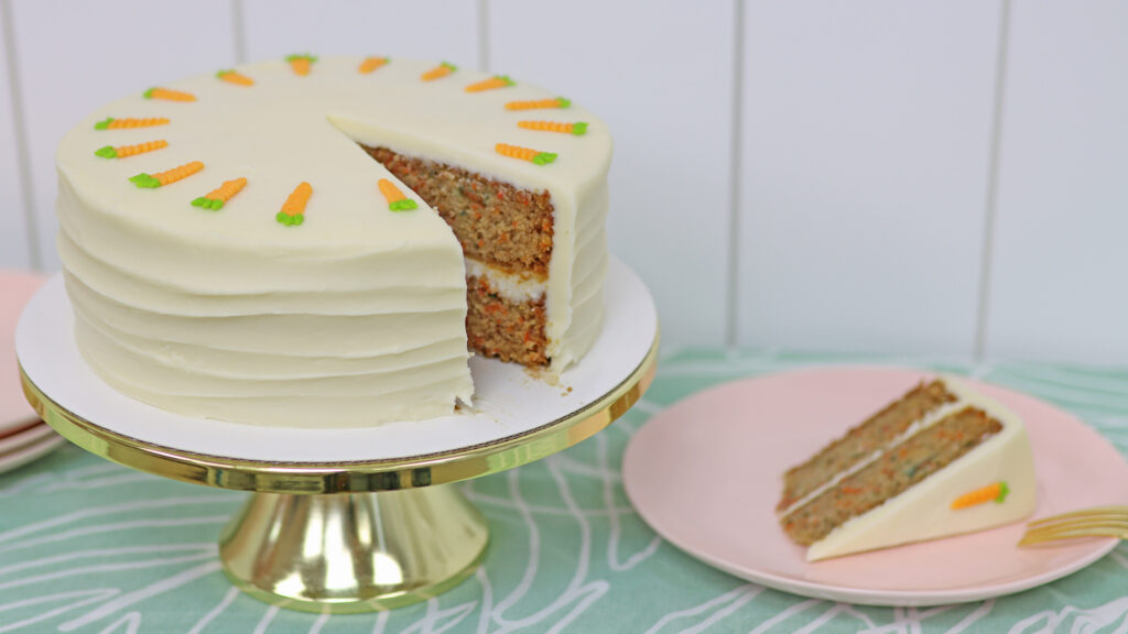 carrot cake with cream cheese frosting decorated with piped buttercream carrots on top