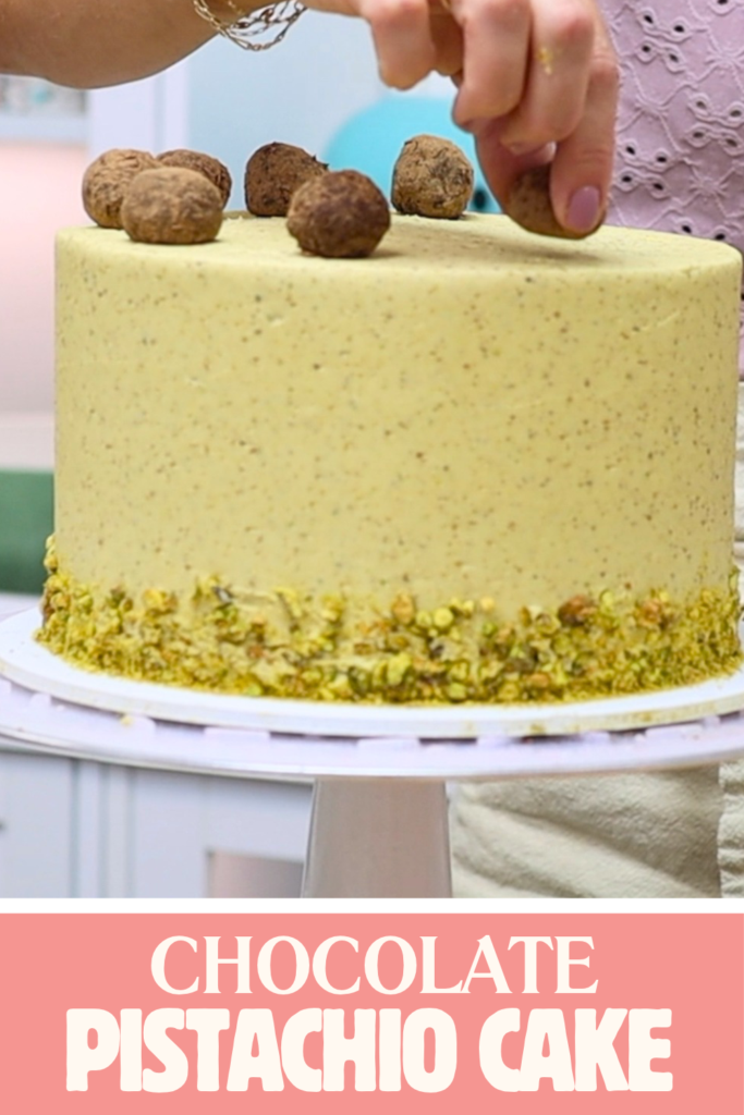 Hands placing truffles around the top edge of a chocolate pistachio cake covered in pale green buttercream.