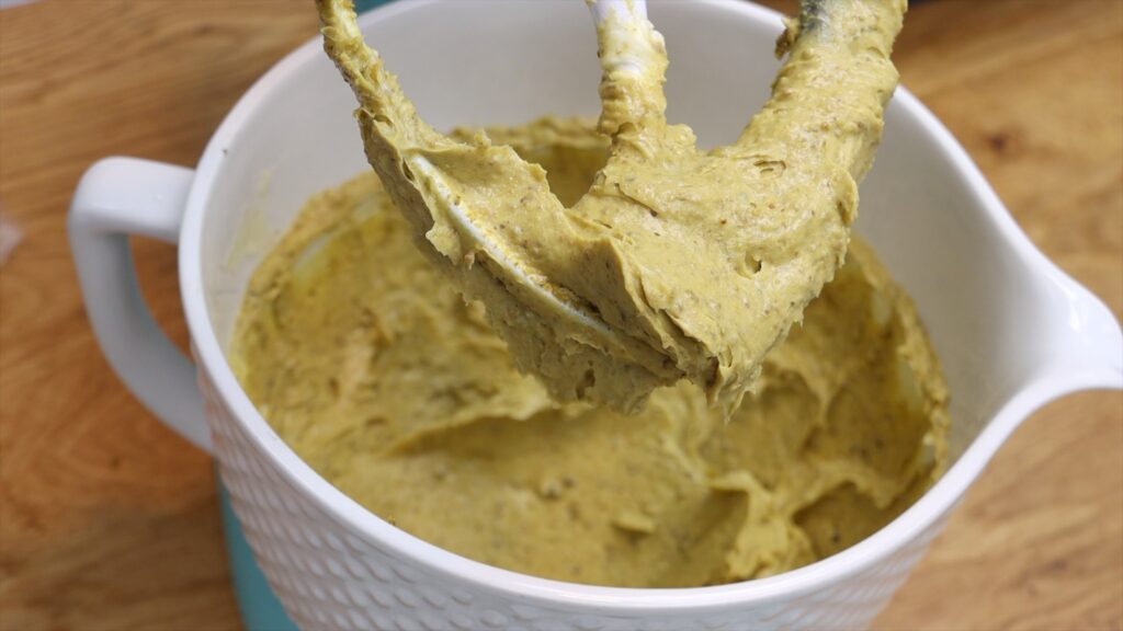 pistachio buttercream frosting made by mixing butter and homemade pistachio paste before adding sugar and milk